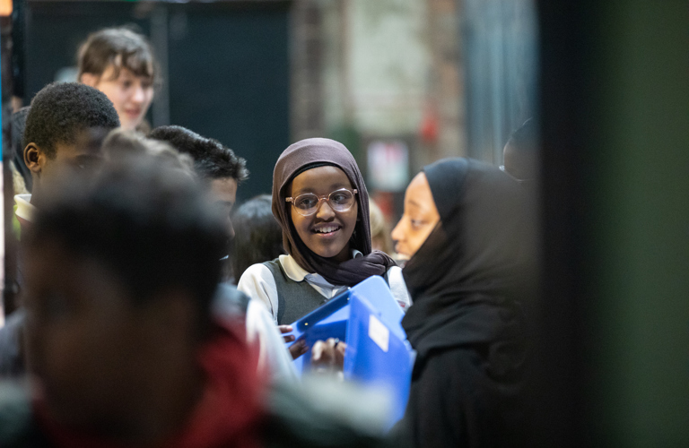 A group of children in conversation holding clipboards 