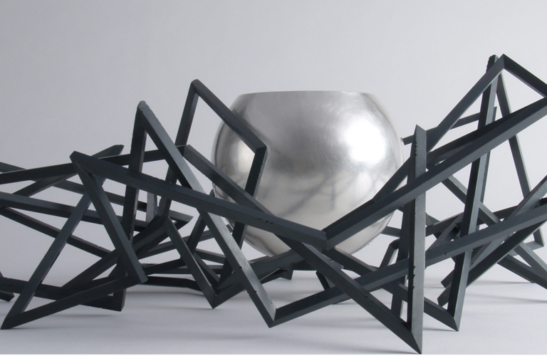 Sculpture with a silver bowl and black, abstract, geometric lines 