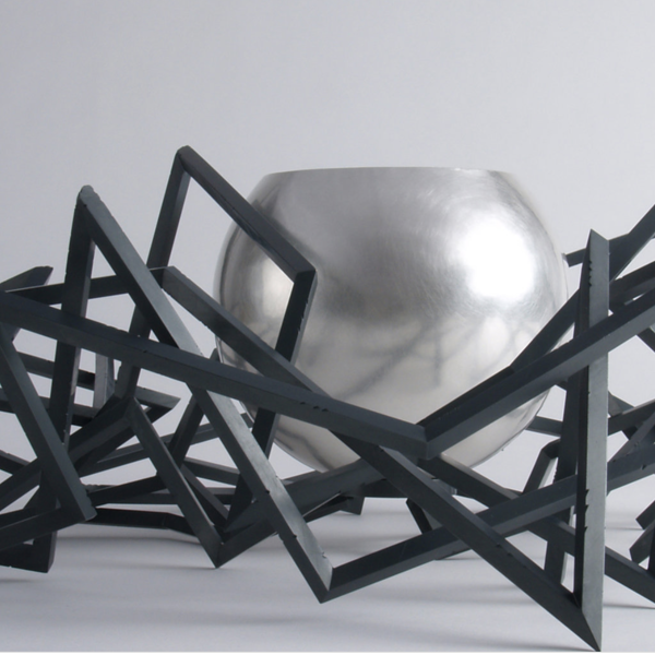 Sculpture with a silver bowl and black, abstract, geometric lines 