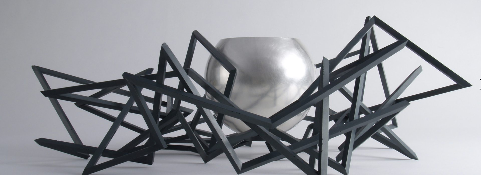 Sculpture with a silver bowl and black, abstract, geometric lines 