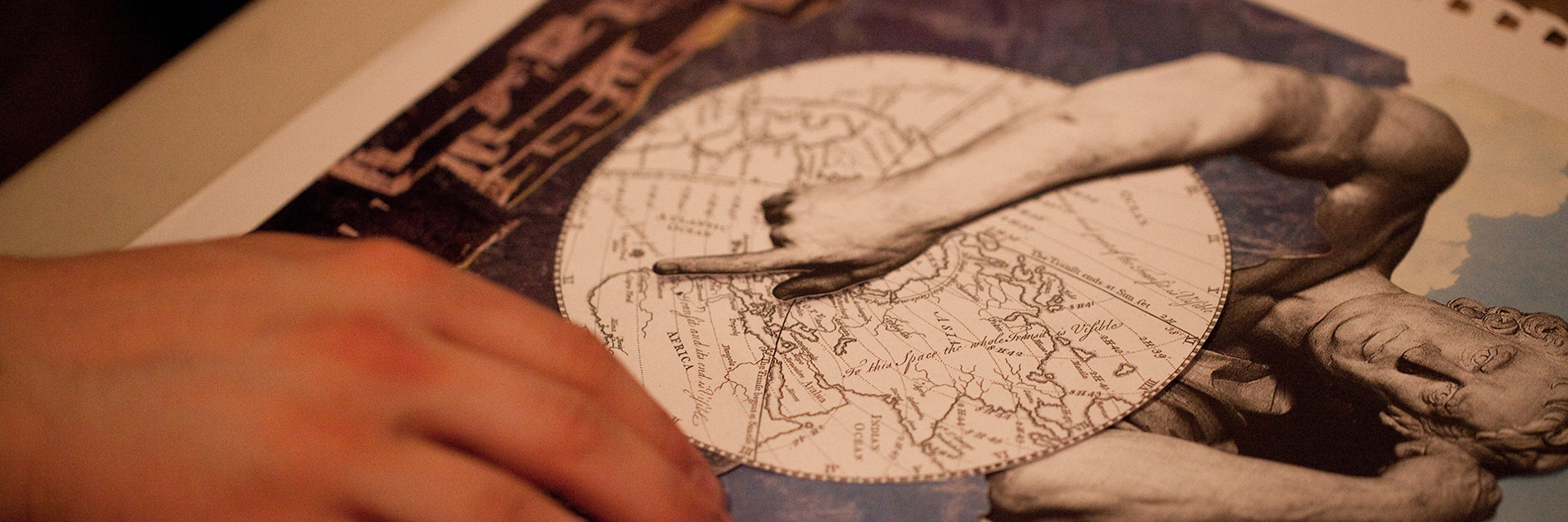 A pair of hands arranging material in a collage, including a map, a photograph of a skyscape and an image of a historic statue.