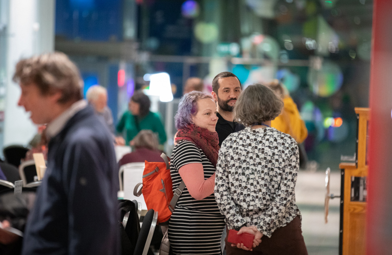 People standing in a group, talking at an evening event at the Millennium Gallery.