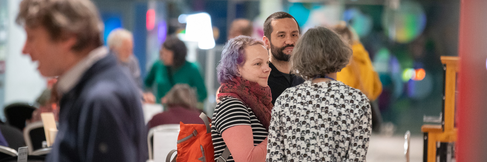 People standing in a group, talking at an evening event at the Millennium Gallery.