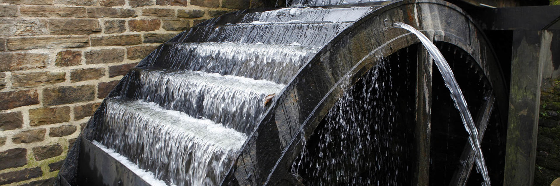 Close up of overshot waterwheel turning as it fills with running water.